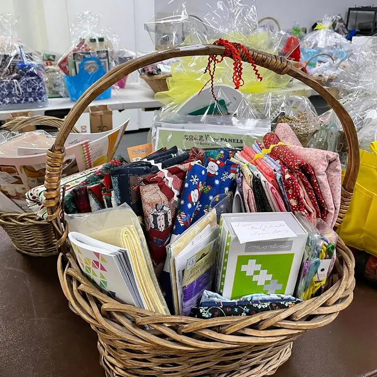 Basket filled with lots of different types of fabric, books, and other objects on a table