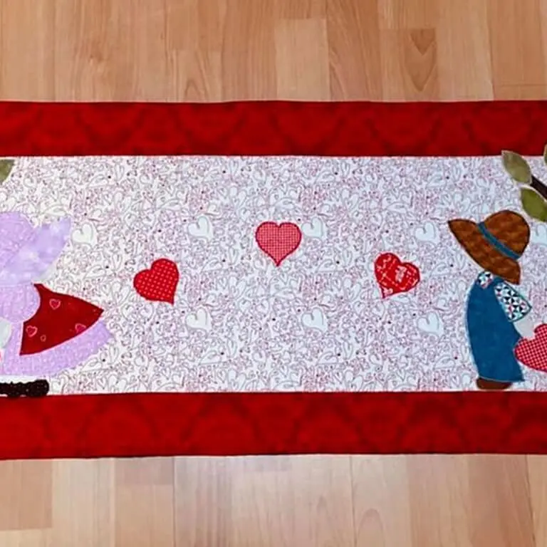 Quilted table runner with a girl and a boy on it, lying on a wooden floor