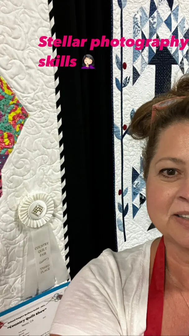 Woman wearing a t-shirt and a red ribbon around her neck, while holding up a quilt