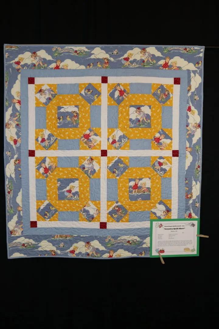 Quilted wall hanging on a black wall, featuring a pattern of yellow, blue, and white colors