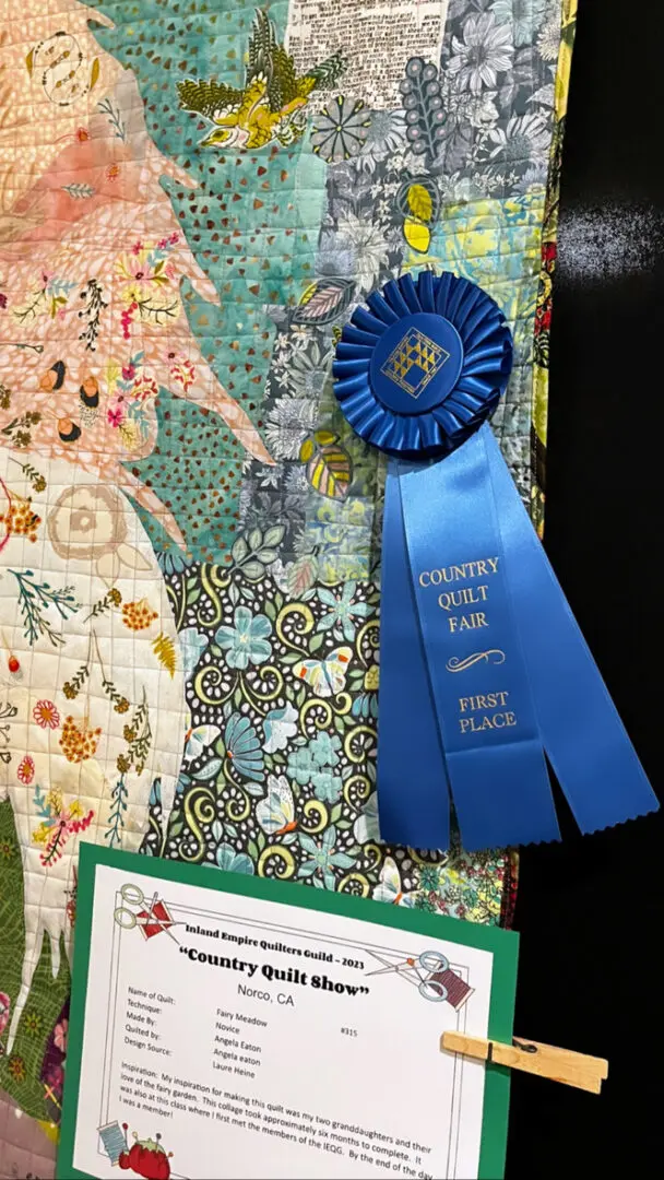 Quilt with a blue ribbon on top of it, along with a paper with text