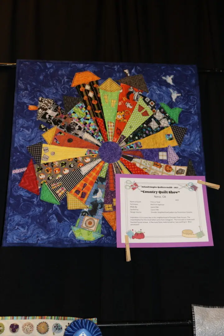 Quilted wall hanging on a black curtain with a certificate attached to it