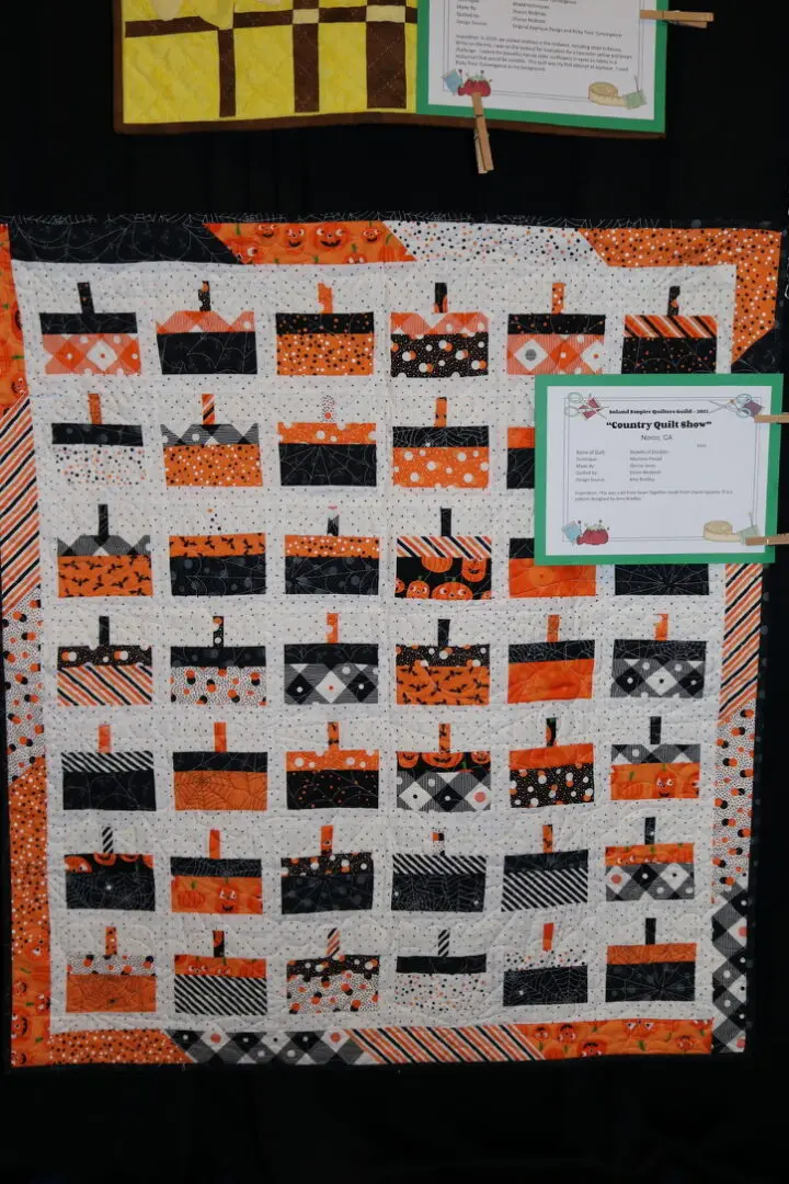 Quilted wall hanging on a wall next to a sign that reads "Country Quilt Show"